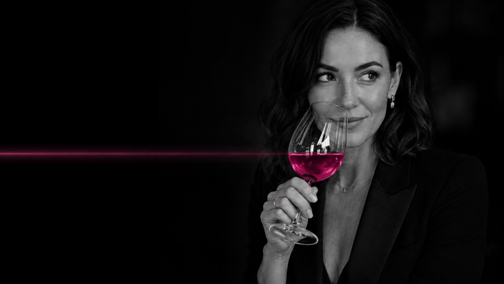Woman behind a wine glass, black and white with a magenta line of light