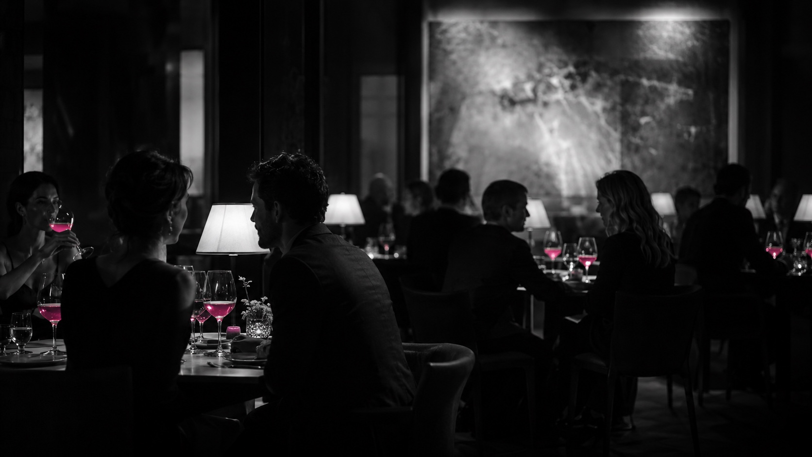 Salle de restaurant sombre le soir, en noir et blanc, les verres de vin rayonnent de magenta