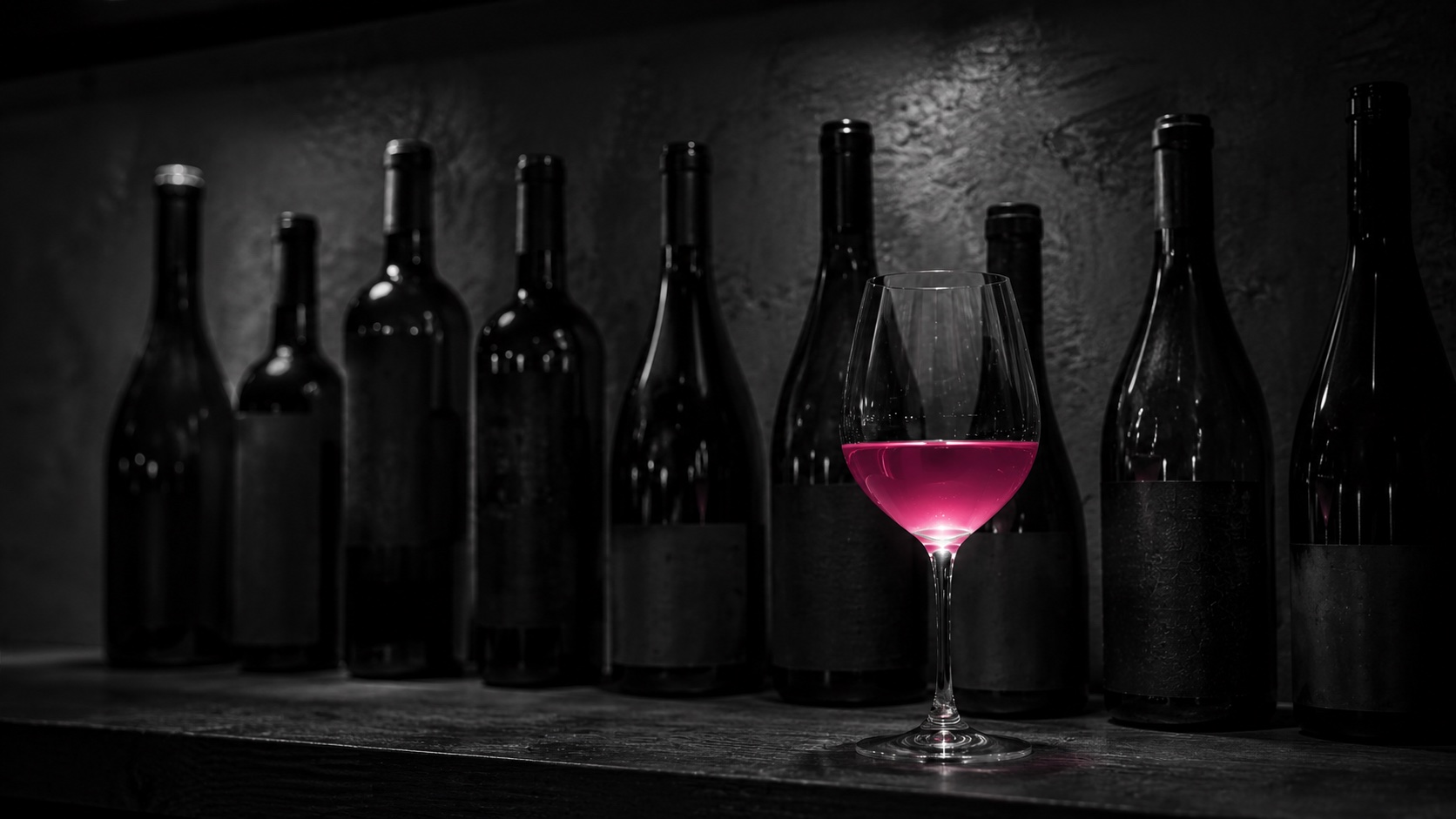 Reihe unterschiedlich gefüllter Weingläser, Schwarzweiß, ein Glas leuchtet magenta