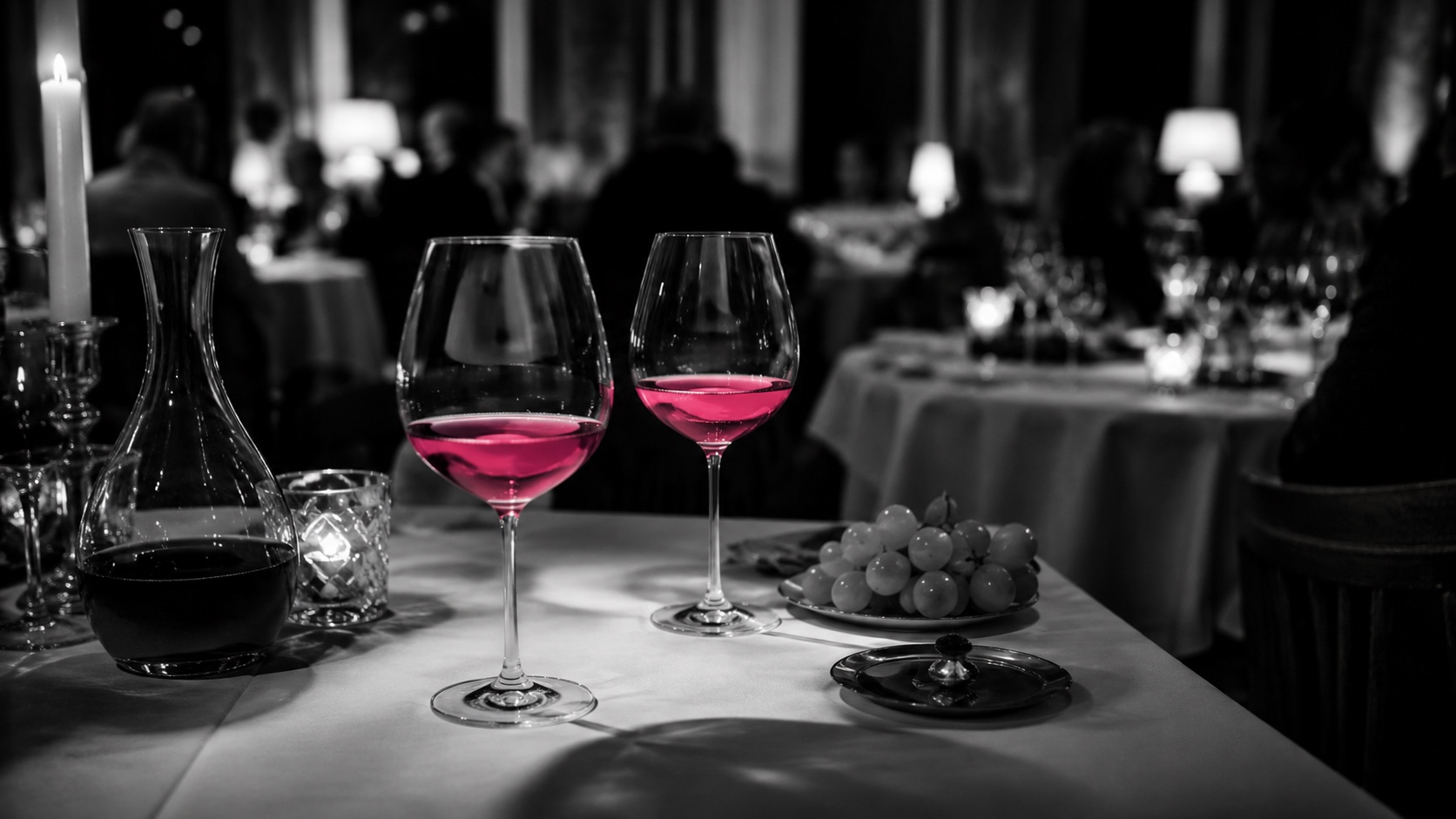 Sala de restaurante escura à noite, a preto e branco, os copos de vinho brilham em magenta