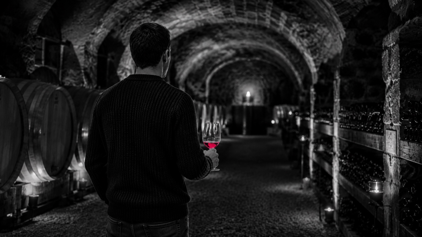 Uma adega de vinhos escura com abóbada de pedra, a preto e branco