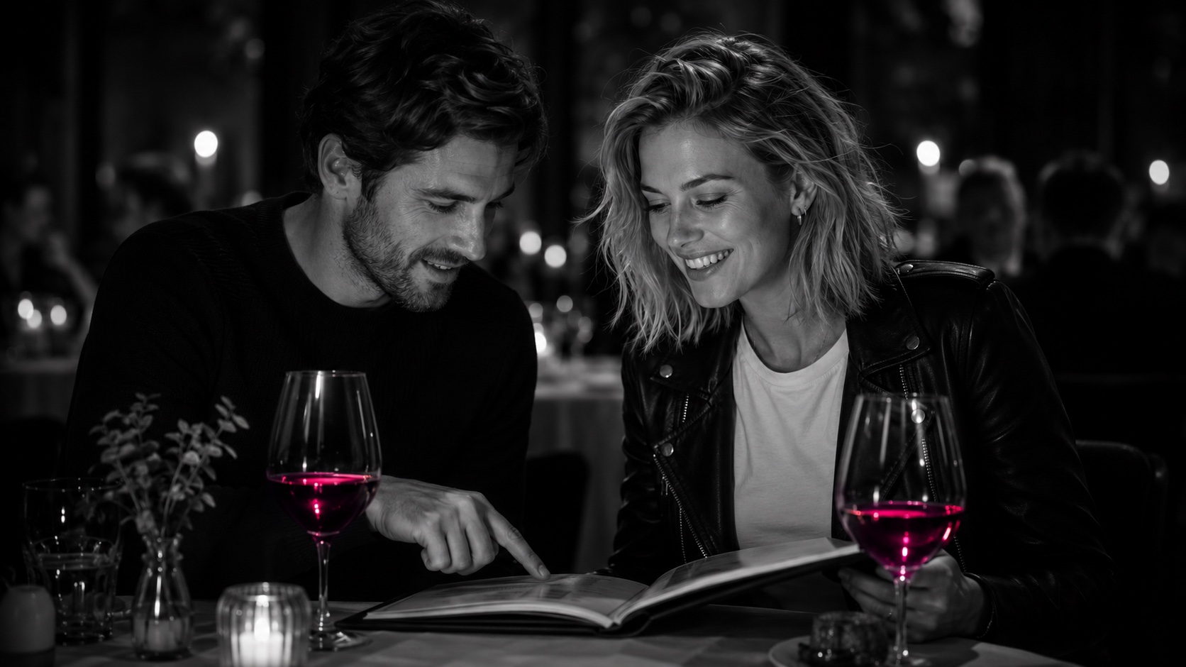 Emma und ihr Freund beugen sich im Restaurant über die Weinkarte, Schwarzweiß, der Wein leuchtet magenta
